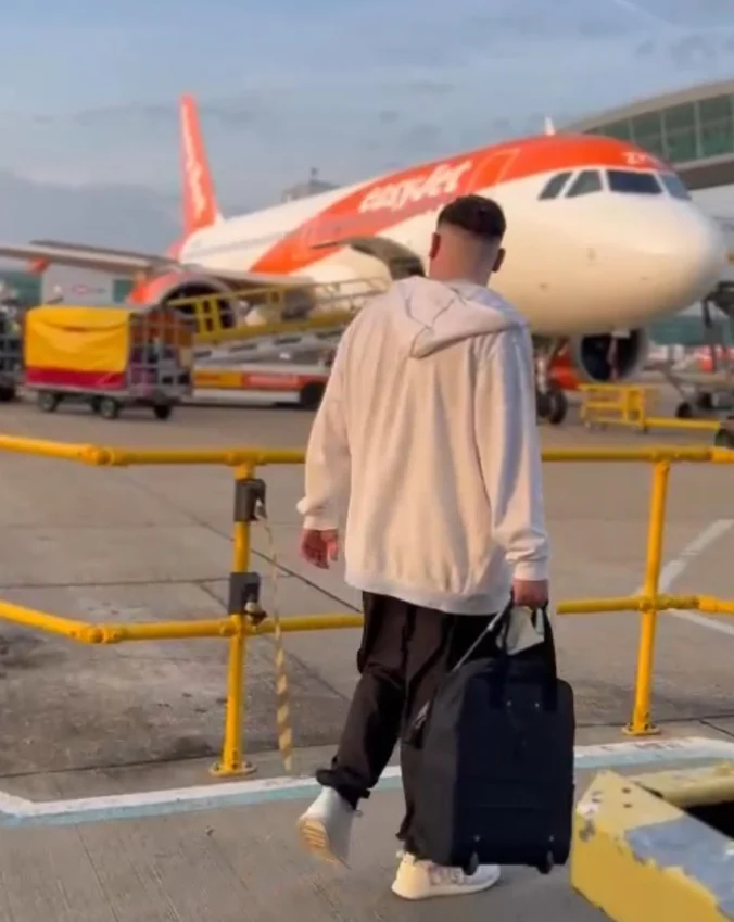 Vextra travelling with luggage beside an airplane